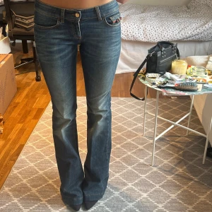 Gucci blå bootcut jeans 70's style - ÄKTA!! Ett par snygga jeans från Gucci med en dekorativ detalj med den klassiska grön röda Gucci färg med gulddetaljerad ”G” på fickan och en läderpatch baktill med ett R tryckt. Jeansen har en bootcut-modell (som är lite vidare) och en klassisk blå denimtvätt. Om mer frågor ställ gärna! Skulle säga att de är 34/36 i hm storlek och 25 Levis storlek och 24 i Abrand jeans. De är ca 10 cm för långa för mig som är 169. Har klackar på mig första bilden!! Inga defekter, skick enligt bild.