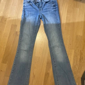 Blå bootcut jeans från Calvin Klein - Snygga ljusblå bootcut jeans från Calvin Klein med broderade bakfickor. Jeansen har normal passform, dragkedja och knapp framtill samt tydlig logga på insidan av linningen. Jeansen har små defekter! En liten blekning syns på bild 3 och sen är byxbena pyttelite strimliga då jeansen var lite långa. Man ser en liten missfärgning på högersida på bild 1! 