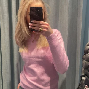 Ljusrosa stickad tröja - Superfin ljusrosa stickad tröja med rund hals och långa ärmar. Tröjan har ribbade muddar vid ärmslut och nederkant, perfekt för lager-på-lager och en söt look. Passar dig som gillar mjuka pasteller och enkel stil.