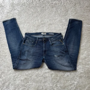 Replay jeans anbass  - Säljer ett par snygga Replay jeans i klassisk blå tvätt i modellen anbass. Jeansen har raka ben, fem fickor och diskreta slitningar framtill för en cool look. Köpta nya från pondus för ett tag sedan men blev inte använda många gånger.