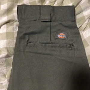 Dickies 874 mörkgröna chinos - Säljer ett par klassiska Dickies 874 chinos i mörkgrönt. Byxorna har raka ben, breda hällor och Dickies-logga ovanför bakfickan. Har två stycket helt oanvända då storleken är för stor! 