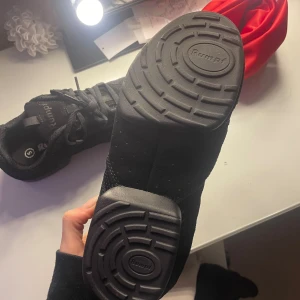 Svarta danssneakers från Rumpf - Svarta dans jazzsneakers från Rumpf dansshopen med mesh och mockadetaljer. Skorna har snörning, platt sula med delad yttersula för extra flexibilitet och rund tå. Perfekta för dans eller träning, med sportig look och bekväm passform. Nästan aldrig använde endast testade. Nu pros 1179 kr 