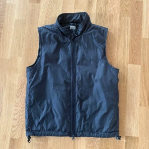 Mörkblå dunväst från Aspesi - Snygg mörkblå dunväst från Aspesi med hög krage och hel dragkedja framtill. Västen har en clean look och justerbar nederkant med snörning. Perfekt att slänga över en hoodie eller tröja för extra värme. Passar dig som gillar stilren och funktionell design. Ny pris 3400kr Skick 9/10 Storlek S