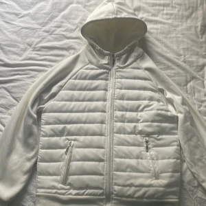 Vit cardigan - Säljer en stilren vit cardigan med huva och dragkedja framtill. Perfekt för dig som vill ha en clean look och hålla dig varm under hösten och våren💯passar dig som är 175-180cm skulle jag säga👍