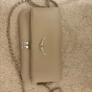 Beige Rock Clutch från Zadig & Voltaire - jättesnygg väska från zadig som var limited edition färg😇 orginalpris 3595 mitt pris 3000! väskan är som helt ny och knappt använd💓två olika band tillkommer, tyvärr är kvittot och påsen borta då jag köpte den för ca 1,5 år sen💗