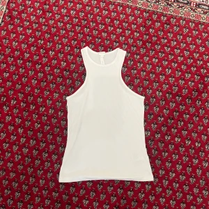 Vit ribbad linnetopp från H&M - Säljer en vit ribbad linnetopp från H&M i storlek M. Toppen har en ärmlös design med breda axelband och rund halsringning. Materialet är mjukt och stretchigt med 94% modal och 6% elastan, vilket gör den riktigt skön och följsam.