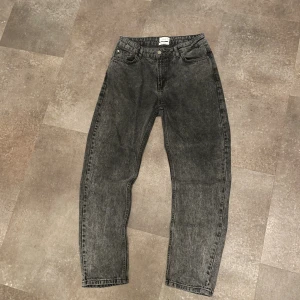 Svarta loose fit jeans från Grunt - Säljer ett par svarta tvättade jeans från Grunt i loose fit-modell. Jeansen har fem fickor, knappgylf och är tillverkade i ekologisk bomull. Snyggt avslappnad passform och klassisk look som funkar till det mesta. Lappen på baksidan har tyvärr lossnat längst ner lite.