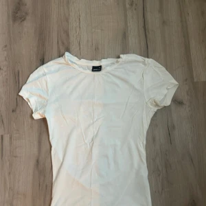 Vit basic t-shirt från Gina Tricot - Enkel och stilren vit t-shirt från Gina Tricot i storlek XS. T-shirten har rund halsringning och korta ärmar, perfekt för en clean och avslappnad look. Tillverkad i mjuk bomull som känns skön mot huden.