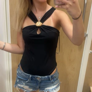 Svart body!! - Snygg svart body med twistad halterneck och en stor guldfärgad detalj framtill. Köpt i somras o verkligen så snygg, använd 1 gång🩵🩵
