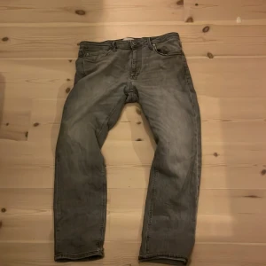 Gråa jeans från Jack & Jones - Säljer ett par gråa jeans från Jack & Jones, modell Regular Clark. Klassisk femficksdesign, rak passform och normal midja. Jeansen är i mjukt denimtyg och har en snygg tvättad look som passar till det mesta. Perfekta för dig som gillar en enkel och stilren vibe.