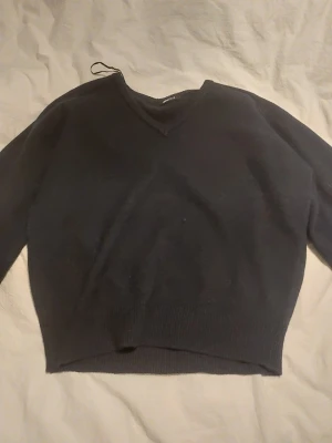 Mörkblå stickad tröja från Gina Tricot - Mysig mörkblå  stickad tröja från Gina Tricot i storlek L. Tröjan har v-ringad hals och ribbade muddar vid ärmslut och nederkant. Perfekt för att hålla sig varm under kyliga dagar och passar till många olika stilar.Endast testad.