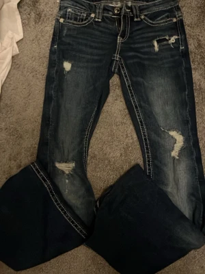 Bootcut jeans med broderade fickor XS - Snygga mörkblå bootcut jeans från Gina Tricot i storlek XS. Jeansen har slitna detaljer framtill, kontrastsömmar och broderade bakfickor med coolt mönster. Materialet är klassisk jeans och passformen är loose med breda ben. Perfekt för dig som gillar statement-jeans!