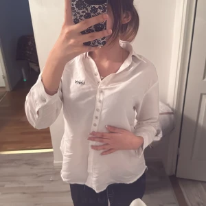 Vit henley-skjorta från Point - Snygg vit henley-skjorta från Point med klassisk krage och långa ärmar. Skjortan har flera knappar framtill och en broderad Levi's-logga på bröstet. Tillverkad i ett mjukt och lätt tyg som känns skönt mot huden. Perfekt för en clean och stilren look. OBS!! Har några sminkfläckar som går säkert bort i tvätten