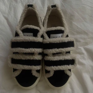 Svarta Inuikii sneakers - Unika svarta sneakers från Inuikii med breda, fluffiga teddyband i vitt och chunky vit sula. Skorna har en cool kontrast mellan svart mocka och mjukt teddyfoder, perfekt för dig som vill sticka ut. Snygg och bekväm modell med rund tå och platt sula. Passar perfekt nu till hösten. Köpta för ca 2500kr. Sitter som str 41. sulorna har blivit lite missfärgade (ingenting som märks) och en liten bit av sular har lossat. Går att fixa hos skomakare för ungefär 250kr skriv privat för fler bilder.