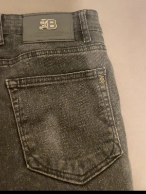 Burberry svarta skinny jeans W33/L34 - Svarta skinny jeans från Burberry, modell 5527. Jeansen har klassisk femficksdesign, knappgylf med Burberry-logga och detaljer i silver. Materialet är 99% bomull och passformen är tight. Snyggt B-emblem på bakfickan och stilren look.