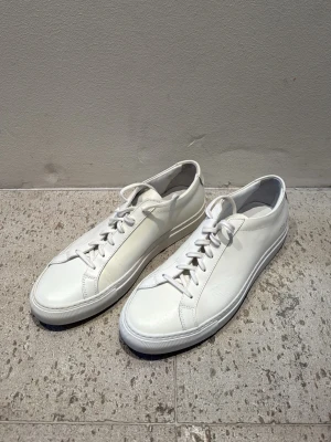 Common projects Achilles - Säljer dessa skor då dom stått länge nu och ej använts tyvärr! Super snygga enkla vita skor som passar till mycket! Köptes för 3999kr och säljer för 1998