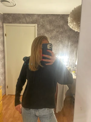 Mörkgrå stickad hoodie från VERO MODA - Mörkgrå ribbad hoodie från VERO MODA med justerbar dragsko i huvan. Mjukt, värmande material och en snygg, enkel design som passar både till vardag och mys.