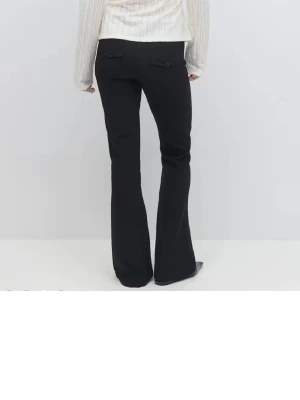 Svarta bootcut kostymbyxor - Snygga svarta kostymbyxor i bootcut med klassisk midja. Byxorna har två knappar framtill, bälteshällor och fickor med lock bak. Materialet är slätt och ger en stilren look som funkar till många olika outfits. Bara använda några enstaka gånger ☺️