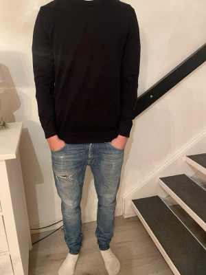Tiger of Sweden Jeans - Säljer ett par blå jeans med snygga slitningar och lätt tvättad look. Modellen har klassisk femficksdesign och en normal passform. Feta jeans som passar bra till alla olika tillfällen