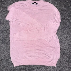 Ljusrosa tröja/kofta - Säljer en ljusrosa tunt stickad tröja från lager 157 med rund hals och långa ärmar. Tröjan har en enkel och clean design med ribbade muddar vid ärmslut och nederkant. Endast använd 1 gång!