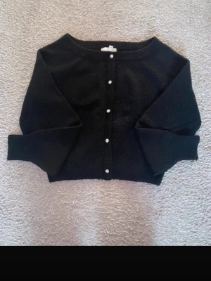 Svart kofta med glittriga knappar H&M - Svart kofta från H&M i storlek S. Koftan har långa ärmar, rund hals och är stickad i mjukt material. Framtill sitter glittriga, pärlformade knappar som ger en extra touch. Kommer inte till användning längre. Hör av er vid funderingar!!❤️☺️