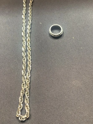 Ring och kejda - Bilden visar en silverfärgad kedja och en ring, ingen väst finns med på bilden.