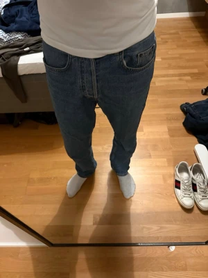 Blå jeans från J.Lindeberg 30/32 - Säljer ett par klassiska blå jeans från J.Lindeberg i storlek 30/32. Jeansen har rak passform, fem fickor och normal midja. Materialet är slitstark denim i bomull och färgen är en snygg mellanblå ton. Perfekt för dig som gillar stilrena och tidlösa jeans.