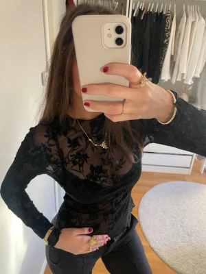 Svart blommig meshblus - Säljer en svart långärmad festtopp! Perfekt nu till nyår eller fest! Seetrue  