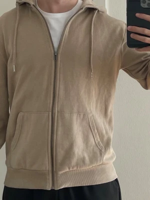 Ziphoodie  - Beige ziphoodie. Storlek S.