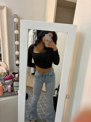 Ljusblå bootcut jeans med låg midja - Säljer ett par ljusblå jeans med bootcut-modell och låg midja. Jeansen har klassisk femficksdesign, dragkedja och knapp framtill. De är slitna längst ner. 