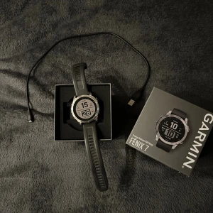 Garmin Fenix 7 - 47mm - Säljer min fantastiska klocka, då jag fick en ny i julklapp. Garmin Fenix 7 multisport GPS-klocka i mycket fint skick, komplett med originalförpackning och laddkabel. Robust design med fiberförstärkt polymer och 316L rostfritt stål, vattentät till 100 meter. Perfekt för träning och äventyr, med lång batteritid och avancerade funktioner. Klockan har en väldigt liten repa på glaset, syns bara om man kollar noggrant. Pris kan diskuteras, men inga skambud!