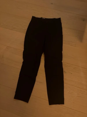 Marinblå kostymbyxor från H&M, strl 36 - Marinblå kostymbyxor från H&M i storlek 36. Byxorna har smal passform, midwaist och klassisk rak design med bälteshällor och diskreta bakfickor. Perfekta till en snygg look och gjorda i mjukt bomullsmaterial med lite stretch.