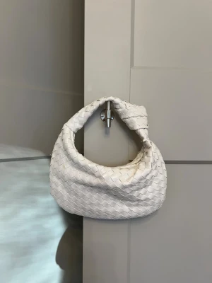 Vit flätad axelväska i skinn Bottega liknande - Säljer en snygg vit axelväska med flätad design och mjuk, rundad form som liknar Bottega väskan. 