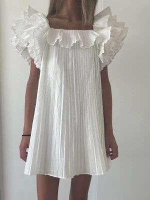 Vit plisserad kortklänning med volang - INTRESSEKOLL så sjukt fin och eftertraktad klänning från Zara!! Endast använd vid 1 tillfälle så i nyskick 💓💓 säljer endast vid bra bud så kom med prisförslag, första bilden är min egna 💓