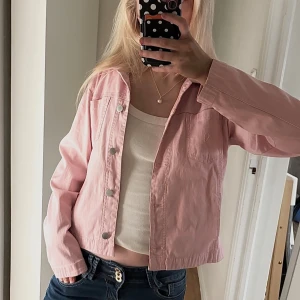 Ljusrosa jeansjacka från Premoda - Säljer en ljusrosa jeansjacka från Premoda Collection i storlek 38. Jackan har klassisk krage, silverfärgade knappar framtill och en bröstficka. Materialet är jeans och passformen är normal. Perfekt att styla med dina favoritjeans eller kjol.