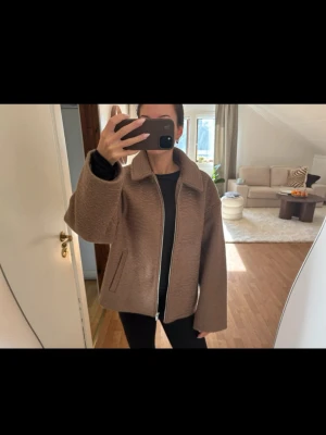 Beige teddyjacka med dragkedja - Säljer en beige teddyjacka med oversized passform och bred krage. Jackan har lång ärm, två fickor framtill och stängs med en silverfärgad dragkedja. Perfekt för dig som gillar en chill och trendig look. Materialet är mjukt och fluffigt, vilket gör den extra mysig.