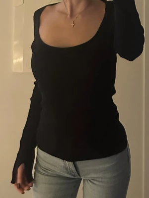 Svart ribbad långärmad topp - Säljer en svart ribbad topp med lång ärm och djup, rundad halsringning. Modellen är slim och sitter snyggt mot kroppen. Inköp H&M