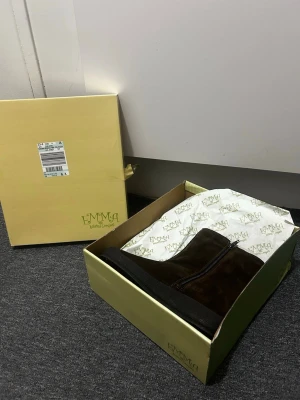 Bruna mockakängor från Emma, strl 37 - Säljer ett par bruna kängor från Emma i storlek 37. Skorna är tillverkade i mjuk mocka med dragkedja på sidan och har en platt, mörk sula. Perfekt för dig som gillar enkel och stilren design med naturliga material. Nypris ca 800-900kr 