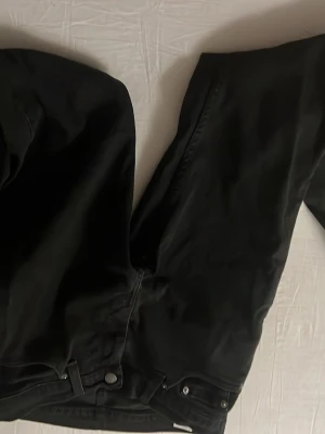 Svarta Levi's 511 jeans - Svarta Levi's 511 jeans med klassisk rak passform och fem fickor. Jeansen har metallknappar och Levi's röda etikett på bakfickan. Materialet är slitstark jeansbomull och färgen är helsvart, vilket ger en clean och tidlös vibe. W30 L30