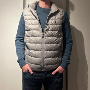 Ljusgrå dunväst från Polo Ralph Lauren - Grå dunväst från Ralph Lauren Storlek: M (Killen på bilden är 183cm) Köpt för 1900