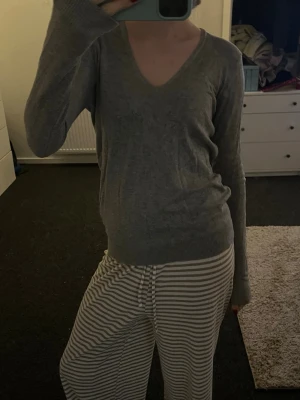  v-ringad tröja - Säljer en  grå stickad tröja med v-ringning och långa ärmar. Perfekt att slänga på sig under kyligare dagar🌪️