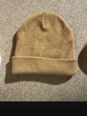 Mössa  - Bilden visar en beige stickad mössa, passar både barn o vuxen 