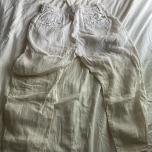 Vita linnebyxor Bruun & Stengade - Snygga vita linnebyxor från Bruun & Stengade i slim fit-modell. Byxorna har dragsko i midjan, resår och diskreta bakfickor med detaljer i metall. Perfekta för en chill och stilren look under varma dagar.