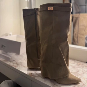 Khakifärgade mockastövlar med klack - Helt nya fick hem dom idag! Dom är stilrena stövlar i khakifärgad mocka från Lululia. De har hög klack, spetsig tå och en dekorativ detalj upptill. Dragkedja på insidan för enkel påtagning. Perfekta för dig som vill ha en trendig och elegant look. Köptes för 600kr 