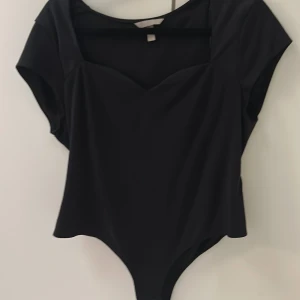 Svart body från H&M med sweetheart-ringning - Svart body från H&M med korta ärmar och snygg sweetheart-ringning. Sitter tight och har en stilren look som passar till många outfits. Gjord i mjukt, stretchigt material för en bekväm passform. Storlek L men passar  XL, och M.