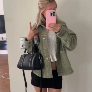 Populär jeansjacka med knappar - Snygg grön jeansjacka med klassisk krage och stora fickor framtill. Jackan har knappar hela vägen och en loose passform som ger en avslappnad vibe. Perfekt att slänga över en topp eller hoodie för en cool look. Jackan är använd men inga större defekter. 