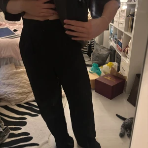 Kostymbyxor NA-KD - Snygga NA-KD kostymbyxor i en pösigare form. Är högmidjade och har två fickor fram och två låtsas fickor där bak. Är i storlek 38 och knappt använd.