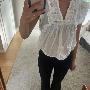 Vit blus med volang från Neo Noir - Supersöt vit blus från Neo Noir! Lappen har ett namn skrivet på sig.