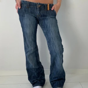 Blå bootcut jeans - Snygga blå jeans med bootcut passform och låg midja. Jeansen har klassisk femficksdesign, slitningar.
