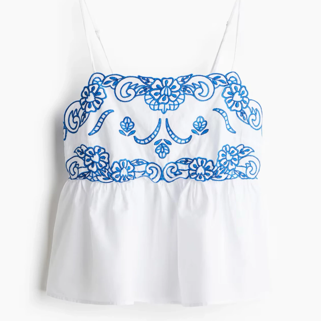 Vit broderad linnetopp med blå detaljer